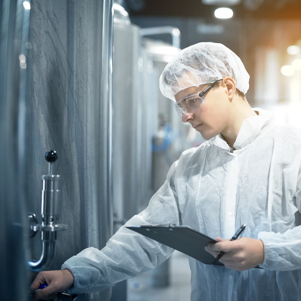 Technician inspecting stainless steel pharmaceutical equipment