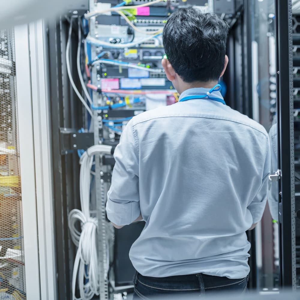 Engineer working in a server room holding a laptop